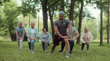 Parktaki eğitimden önce bir grup yaşlı sporcu birlikte ısınıyor.