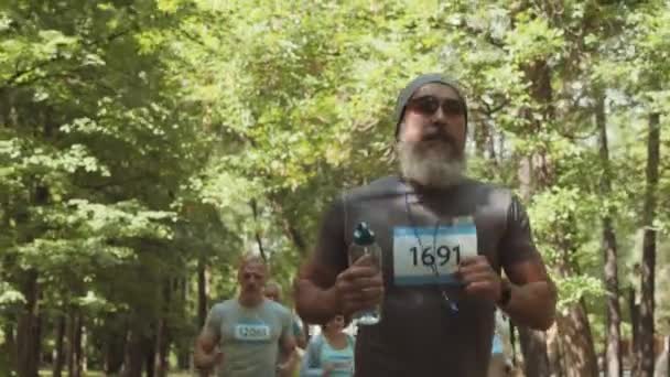 公園を走るスポーツウェアを身に着けているいくつかのシニアアスリートの中ショット — ストック動画