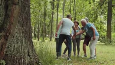 Spor kıyafetleri giymiş, parkta dikilmiş, ellerini birleştirip bir maraton yarışından önce sarılan Kafkasyalı sporcu ve kadınların geniş açılı görüntüleri.