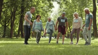 Genç sporcu erkek ve kadınların parkta maraton koşusundan önce ısınma hareketleri.