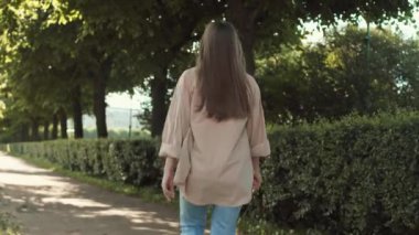 Güneşli yaz parkında zıplayan mutlu, beyaz bir kadının dikiz aynasından bakıp el sallayarak, gülümseyip kameraya bakarken.