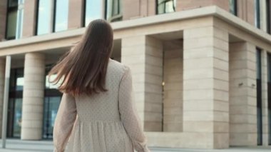 Arkadan bakan, uzun saçlı, mutlu, beyaz bir kadının alışveriş torbaları taşıdığını, binaların önünde yürüdüğünü, sonra başını çevirdiğini, gülümsediğini ve kameraya baktığını gördüm.