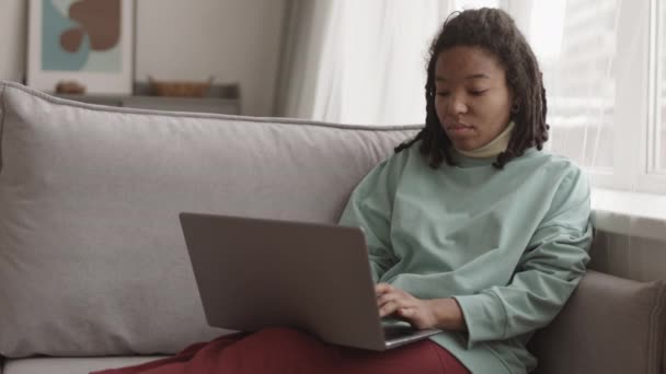 Блокировка Молодой Афроамериканской Женщины Дредами Голове Сидящей Диване Гостиной Печатающей — стоковое видео