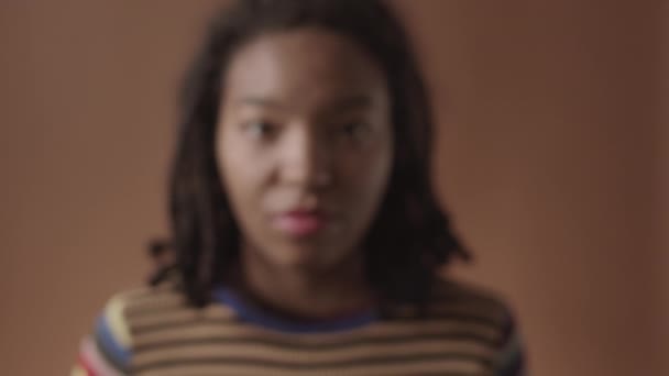 若いですアフリカ系アメリカ人女性のロックダウン問題肌とスタイリッシュなドレッドで彼女の頭の上に近づいてカメラに茶色の背景 — ストック動画