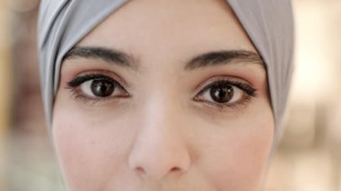Gri tesettürlü, kameraya bakan güzel makyajlı, melez bir kadının üst yüzü.