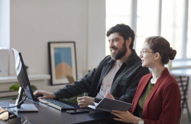 Ofisteki toplantı sırasında bilgisayarla konuşurken gülümseyen sakallı iş adamının yan görüntüsü.