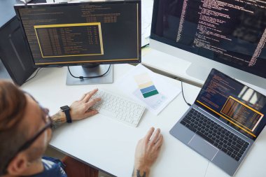 IT geliştiriciler ofisinde birden fazla bilgisayar kullanırken, erkek programcının kod yazarken yüksek açı görünümü, boşluk kopyala