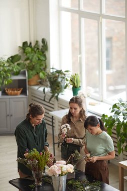 Vertical high angle view at group of florists arranging floral compositions in workshop, copy space