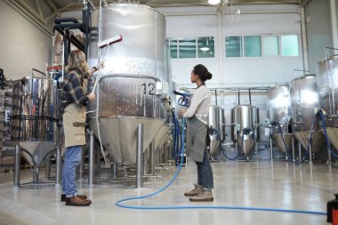 Modern endüstriyel bira fabrikasında çamaşır yıkayan iki işçiye geniş açı görünümü, kopyalama alanı