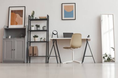 Bitkiler ve soyut sanat eserleri ile dekore edilmiş modern apartmandaki asgari ofis masasının arka planı, kopyalama alanı