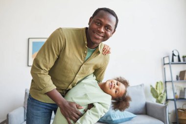 Mutlu Afro-Amerikan baba portresi evde kızıyla oynuyor ve kameraya gülümsüyor, boşluğu kopyalıyor.