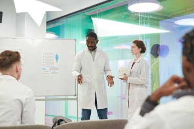 Üniversitedeki tıp seminerinde sunum yaparken izleyicilerle konuşan Afro-Amerikalı bir adamın portresi.