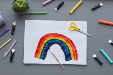 Boya fırçası ve yaratıcı malzemelerle gökkuşağı resminin üst görünümü, boşluğu kopyala
