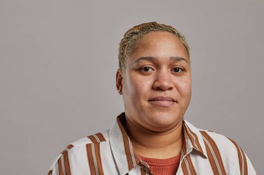 Gri, kopyalama alanına karşı poz verirken kısa kesimli modern melez kadının minimal yakın portresi.