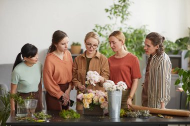 Front view portrait of diverse group of young people attending class on floral art in florists workshop