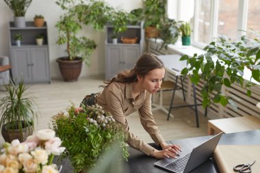 High angle portrait of young female florist using laptop while managing small business workshop, copy space
