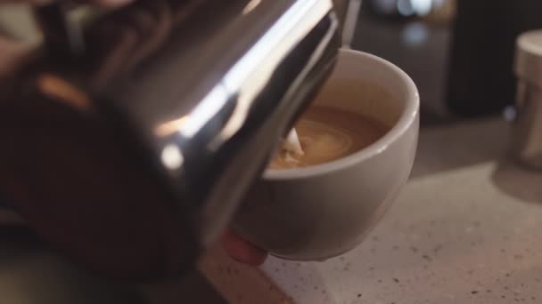 站在工作台上的酒吧里 用无法辨认的咖啡师的手拍了照 并将牛奶从水罐倒入大杯 — 图库视频影像