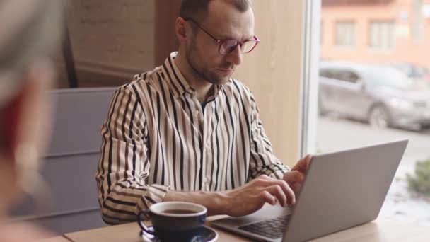 中年白种人商人穿着休闲装和眼镜坐在餐桌旁 在笔记本电脑上工作 然后用卡片支付无接触费 — 图库视频影像