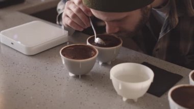 Profesyonel erkek baristanın kafeteryadaki fincanlarda değişik kahve çeşitleri tatmasına yakın çekim. Kahve molası.