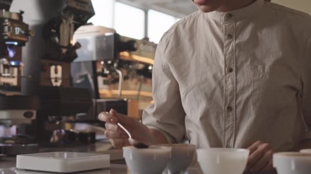 カフェのワークトップに立つプロの女性バーテンダーを傾け レストランのカップテイスターでさまざまな種類のコーヒーを味わうことができます コーヒーの劣化 — ストック動画