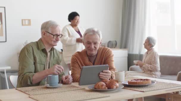 Deréktól Felfelé Két Idősebb Fehér Férfi Asztalnál Beszélgetnek Táblagépet Használnak — Stock videók