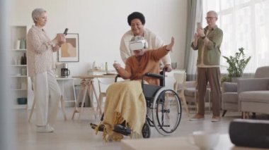 Kulaklık takan mutlu engelli adam, tekerlekli sandalyeyi yan yana hareket ettiren Afrikalı kadın arkadaşı, son sınıf öğrencisi kadın ve erkek, onları akıllı telefonlardan kaydediyor.