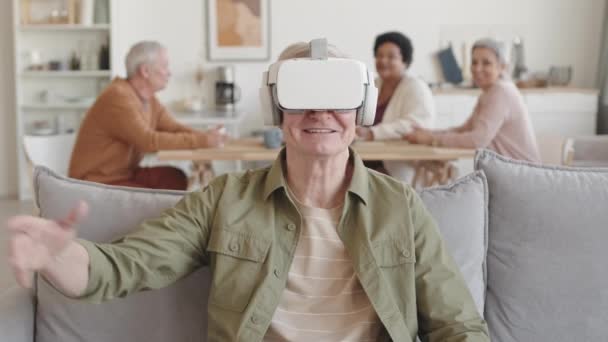 Περίμενε Έναν Χαρούμενο Ηλικιωμένο Που Φοράει Ακουστικά Εικονικής Πραγματικότητας Κάθεται — Αρχείο Βίντεο