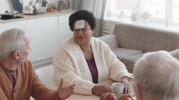 Hohe Freundinnen Sitzen Tisch Spielen Stirndetektivspiel Mit Klebrigen Zetteln Auf — Stockvideo