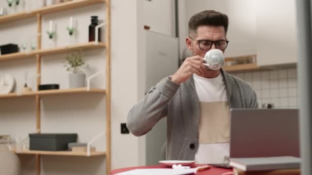 중년의 웨이브 Pov 아파트 테이블에 컵에서 뜨거운 음료를 마시고 노트북 — 비디오