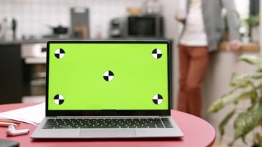 İçerideki yeşil ekranlı taşınabilir bilgisayarın kilitlenmesi, arka planda yürüyen tanınmayan kişinin bulanıklaşması.