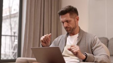 Evdeki koltukta oturan, başka tarafa bakan, düşünen, gülümseyen ve taşınabilir bilgisayarda yazmaya başlayan yakışıklı beyaz adamın belinde.