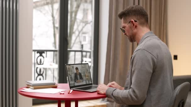 거실에 코카서스 남자의 노트북 컴퓨터를 동료와 비디오 컨퍼런스를 — 비디오