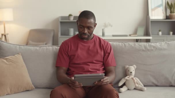 Orta Uzunlukta Bir Afrikalı Adam Tablet Bilgisayar Kullanıyor Kanepede Oturuyor — Stok video