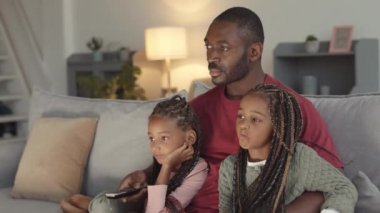 Genç Afrikalı bir adamın kanepede oturup, sevimli küçük kızlarıyla TV izlediği gece kollarında örgüler olan bir film.