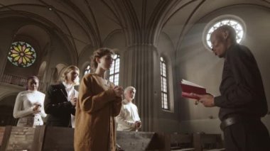 Lüteriyen kilisesinde elinde kutsal İncil 'le siyah pantolon, gömlek ve beyaz yaka giyen ve cemaatin önünde konuşan Afrikalı-Amerikalı bir papazın orta boy fotoğrafı.