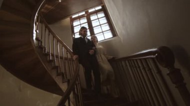Genç Kafkasyalı damat ve gelinin ahşap merdivenlerden aşağı inmesi sonra durup öpüşmeleri ve aşağı inmeye devam etmeleri.