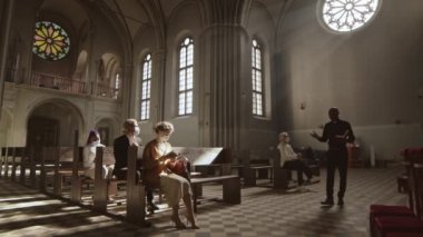 Siyah pantolon, gömlek ve beyaz yakalı Afro-Amerikan rahiplerin Lutheran kilisesi boyunca yürürken ve cemaat üyelerine vaaz verirken geniş bir açı.