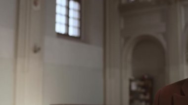 Beyaz ceketli, beyaz gömlekli, beyaz saçlı genç adam Hıristiyan kilisesinde dikilip haç çıkarıyordu.