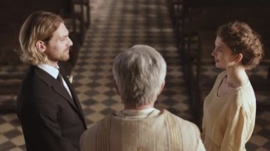 Tanımlanamayan kıdemli papazın vaaz verdiği ve genç beyaz bir adamla büyüleyici gelininin kilisede sunak başında durduğu resmi nikahını kıydığı arka plan.