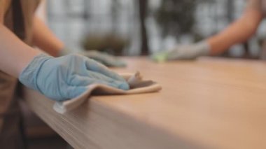 Elleri eldivenli, çerçeveli ve masaları silen tanınmayan insanları kilit altına aldık.
