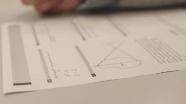Matematiksel problemleri çözen, sınav kağıdına kalemle yazı yazan tanınmayan öğrencilerin elleri kilitlenmiş.