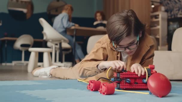 Encierro Colegial Caucásico Con Anteojos Acostado Alfombra Aula Construcción Robot — Vídeos de Stock