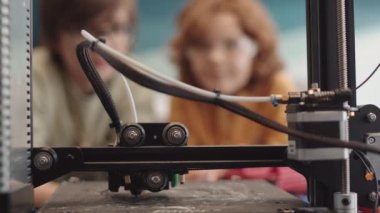 Robot teknolojisi dersi sırasında robotları için 3D yazıcı detaylarını izleyen tanınmayan üç öğrenciyi kapatın.