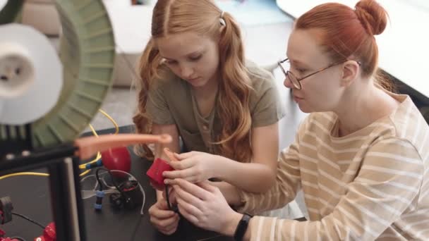 教室の机に腰を下ろし プラスチック製のディテールを使って電子ロボットを作る白人女子高生と若い女性教師の高い角度の眺め — ストック動画