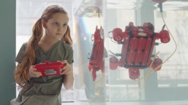 Kafkas öğrenci portresi laboratuardaki su kabında oturuyor ve joystick kullanarak suda yüzen robo botu kontrol ediyor.
