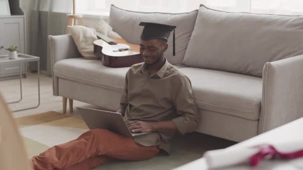 셔츠를 모자를 바닥에 무릎에 랩탑을 온라인으로 졸업식을 가졌다 — 비디오
