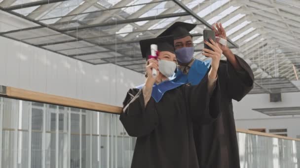 미디엄은 친구가 졸업생 가운을 모자와 마스크를 강당에 스마트폰으로 비디오 전화를 — 비디오