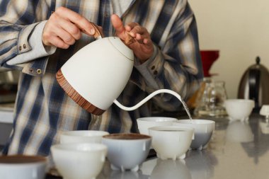 Closeup of unrecognizable male barista pouring coffee to cups in row on bar stand, copy space