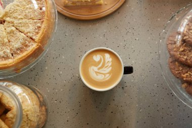 Top down view at cup of coffee with latte art on table in coffee shop or bakery, copy space