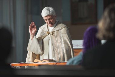 Başrahip kilisede ayin sırasında insanlar için İncil okuyor.